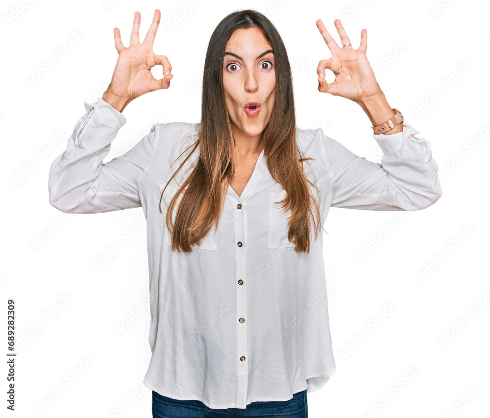 Young beautiful woman wearing casual clothes looking surprised and shocked doing ok approval symbol with fingers. crazy expression Young beautiful woman wearing casual clothes looking surprised and shocked doing ok approval symbol with fingers. crazy expression