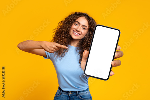 Happy woman pointing at blank smartphone screen © Prostock-studio