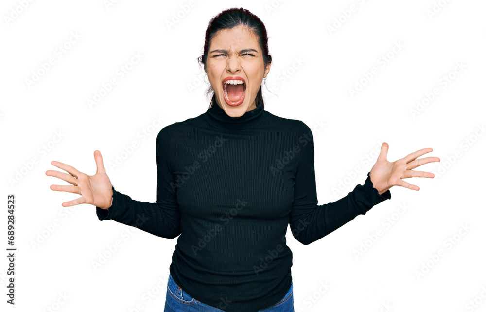 Young hispanic woman wearing casual clothes crazy and mad shouting and yelling with aggressive expression and arms raised. frustration concept. Young hispanic woman wearing casual clothes crazy and mad shouting and yelling with aggressive expression and arms raised. frustration concept.