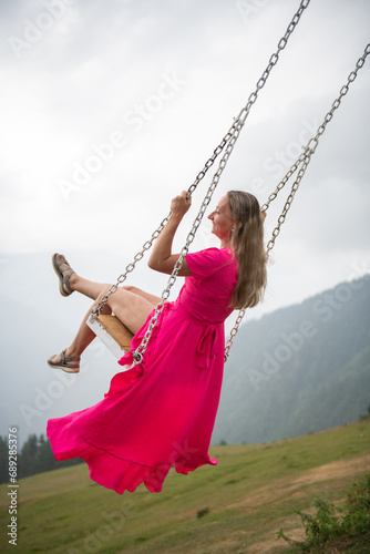 Swinging elegance girl in a pink dress on a swing