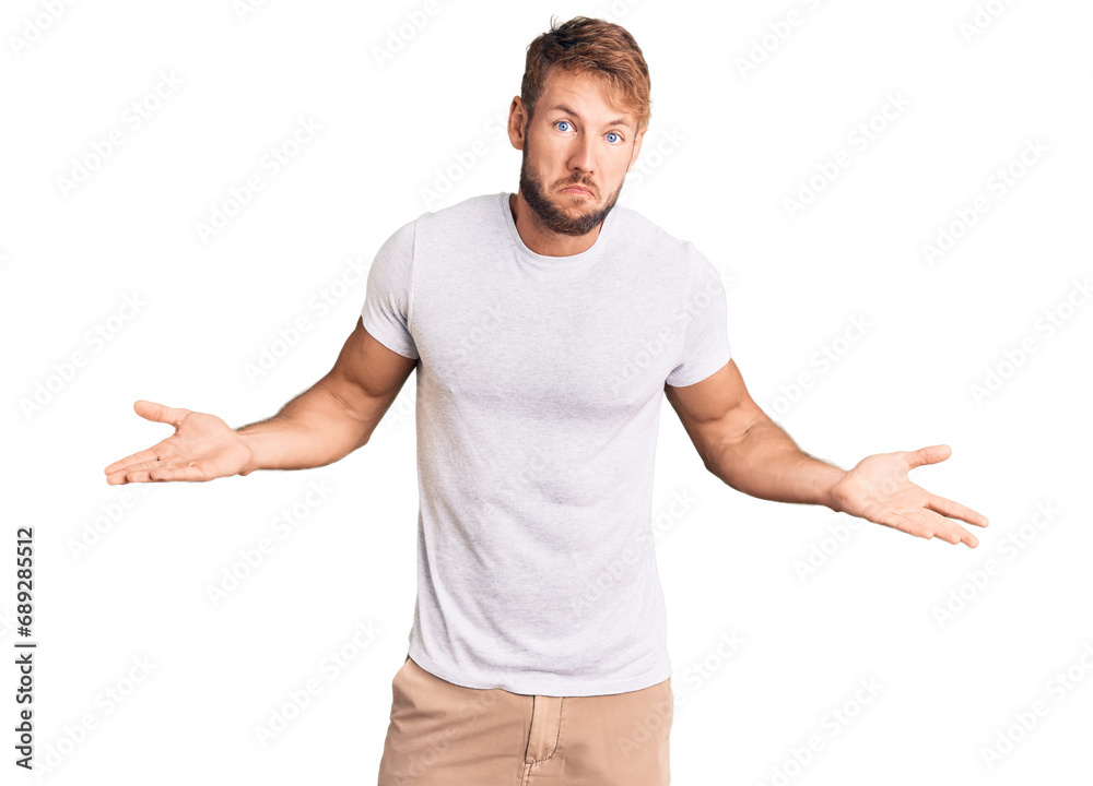 Young caucasian man wearing casual white tshirt clueless and confused expression with arms and hands raised. doubt concept.