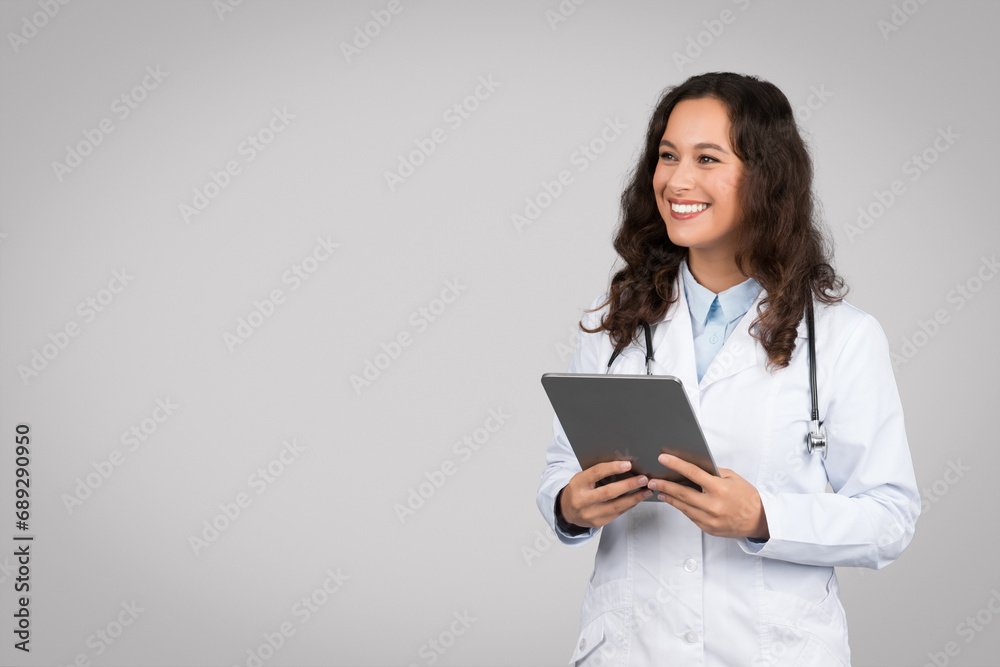 Smiling european woman in medical uniform doctor using digital tablet, looking at copy space for e-healthcare banner Smiling european woman in medical uniform doctor using digital tablet, looking at copy space for e-healthcare banner
