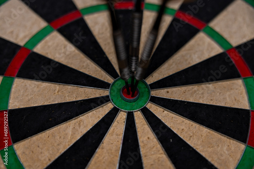 Dart in bulls eye of dartboard with shallow depth of field concept for hitting target.