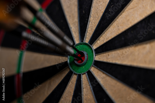 Dart in bulls eye of dartboard with shallow depth of field concept for hitting target.