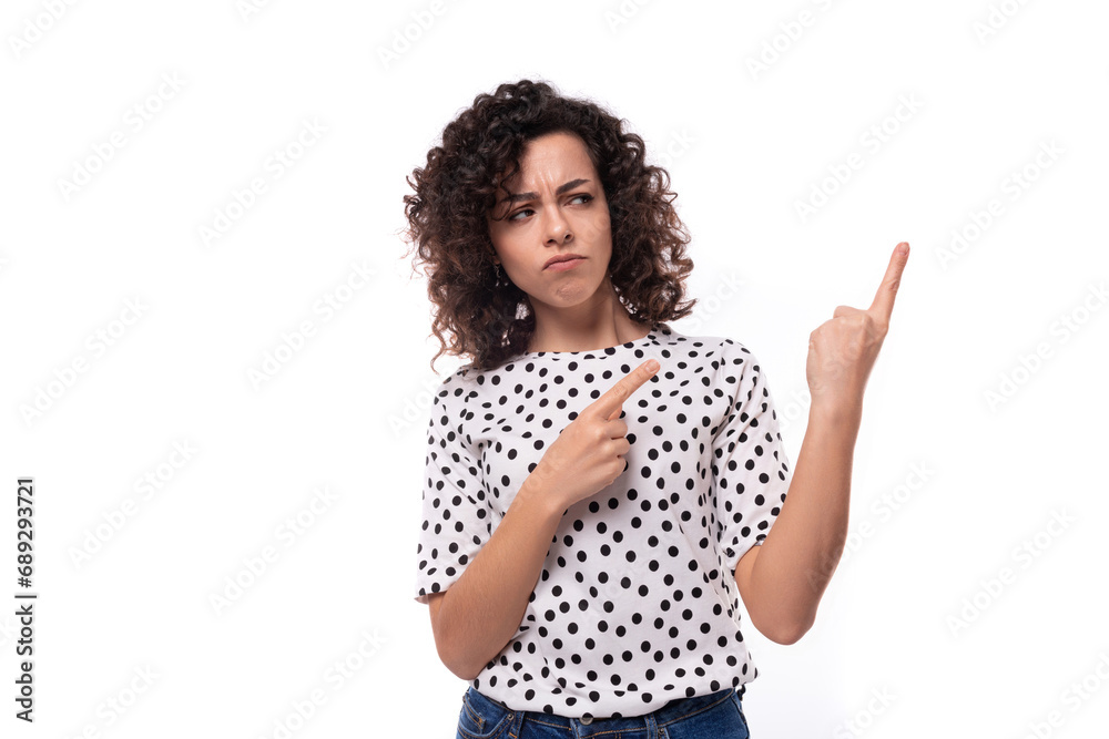 young authentic curly brunette slender lady wearing polka dot short sleeve shirt pointing fingers at ad space young authentic curly brunette slender lady wearing polka dot short sleeve shirt pointing fingers at ad space