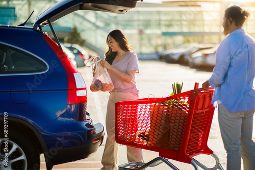 Woman loading groceries into car from cart