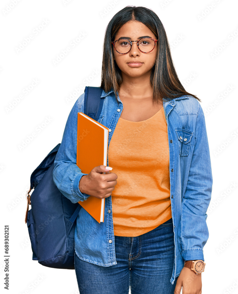 Young latin girl wearing student backpack and holding books relaxed with serious expression on face. simple and natural looking at the camera. Young latin girl wearing student backpack and holding books relaxed with serious expression on face. simple and natural looking at the camera.