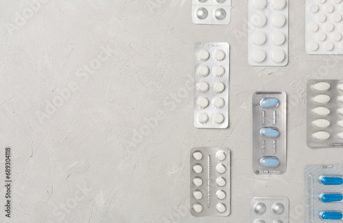 Pills in blister packaging on concrete background, top view