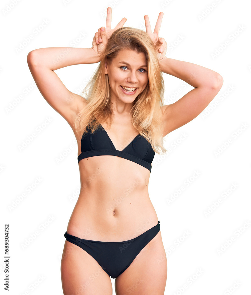 Young beautiful blonde woman wearing bikini posing funny and crazy with fingers on head as bunny ears, smiling cheerful Young beautiful blonde woman wearing bikini posing funny and crazy with fingers on head as bunny ears, smiling cheerful