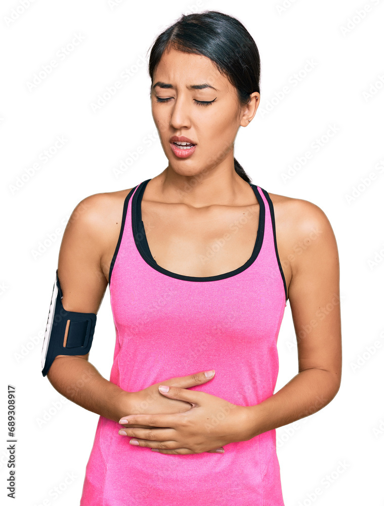 Beautiful asian young sport woman wearing sportswear and arm band with hand on stomach because nausea, painful disease feeling unwell. ache concept. Beautiful asian young sport woman wearing sportswear and arm band with hand on stomach because nausea, painful disease feeling unwell. ache concept.