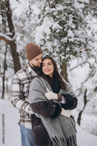 Portrait of a young happy and loving couple having fun in a snowy forest