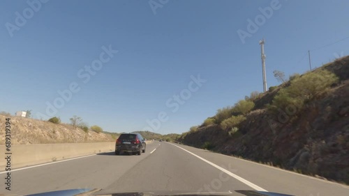 First person view, FPV, from dashcam of car driving along the Algarve Coast in Portugal, driving on the highway. Road trip video in POV, with blue sky photo