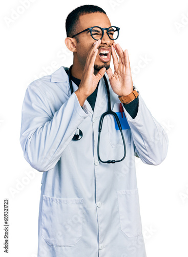 Young african american man wearing doctor uniform and stethoscope shouting angry out loud with hands over mouth