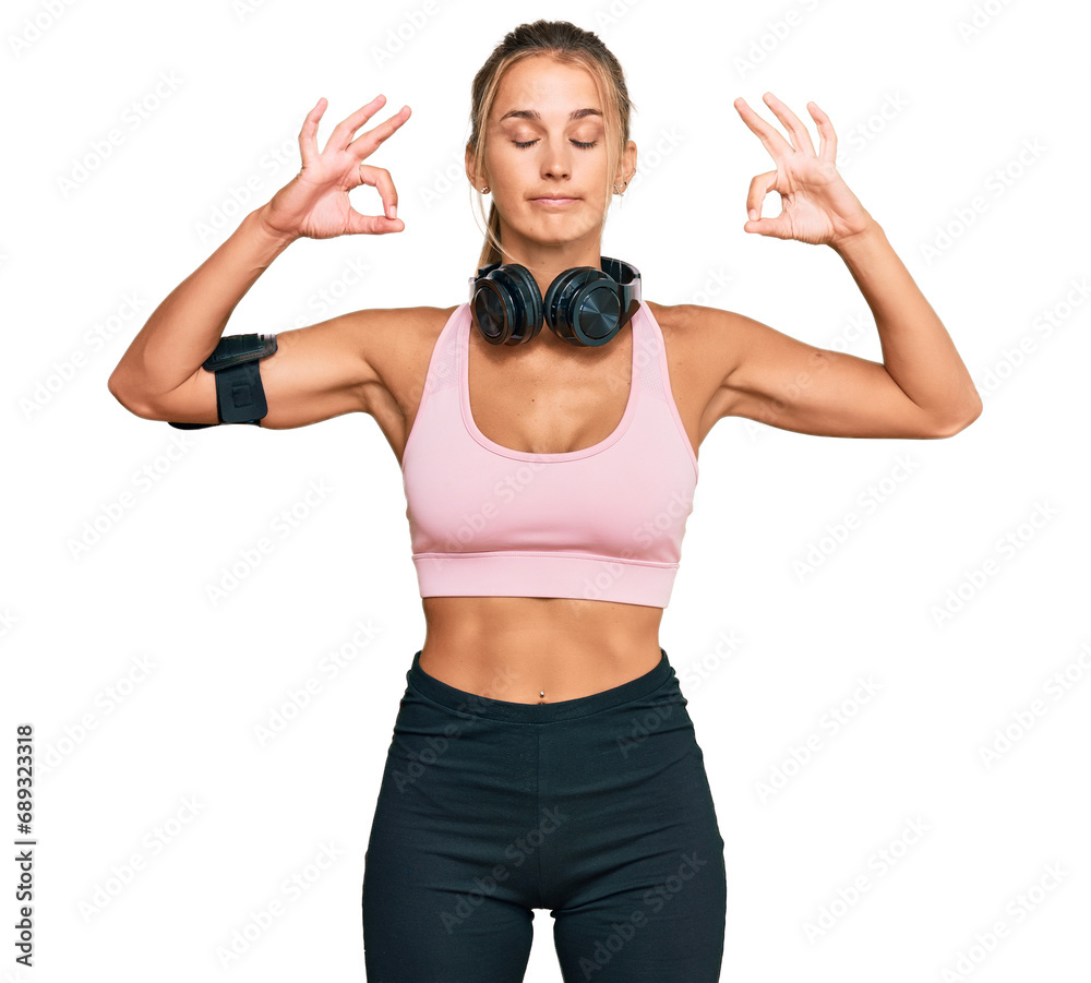 Young blonde woman wearing gym clothes and using headphones relax and smiling with eyes closed doing meditation gesture with fingers. yoga concept. Young blonde woman wearing gym clothes and using headphones relax and smiling with eyes closed doing meditation gesture with fingers. yoga concept.