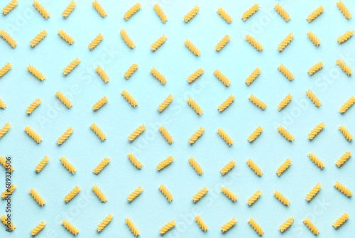 Composition with uncooked fusilli pasta on blue background