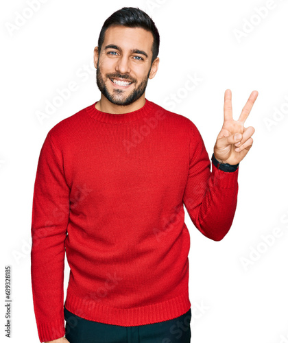 Young hispanic man wearing casual clothes showing and pointing up with fingers number two while smiling confident and happy. © Krakenimages.com