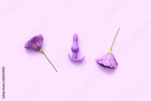 Anal plug from sex shop and beautiful eustoma flowers on purple background photo
