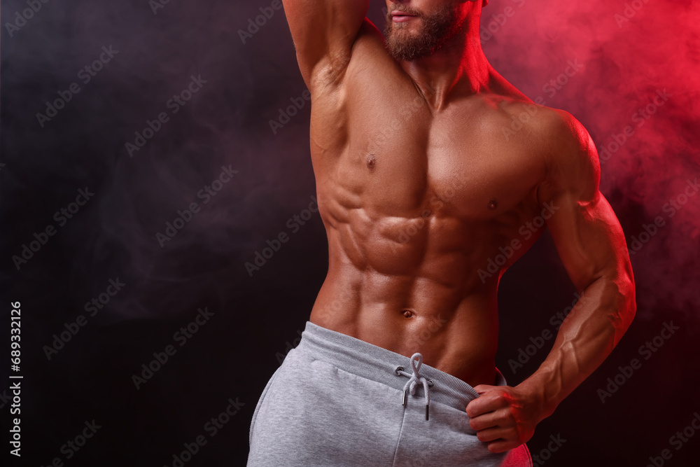 Young bodybuilder with muscular body in smoke on color background, closeup. Space for text