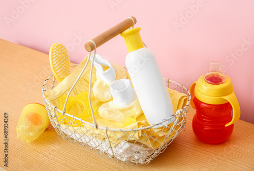 Gift basket for baby on table near pink wall in room, closeup