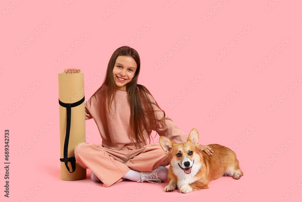 Sporty little girl with fitness mat and Corgi dog on pink background Sporty little girl with fitness mat and Corgi dog on pink background