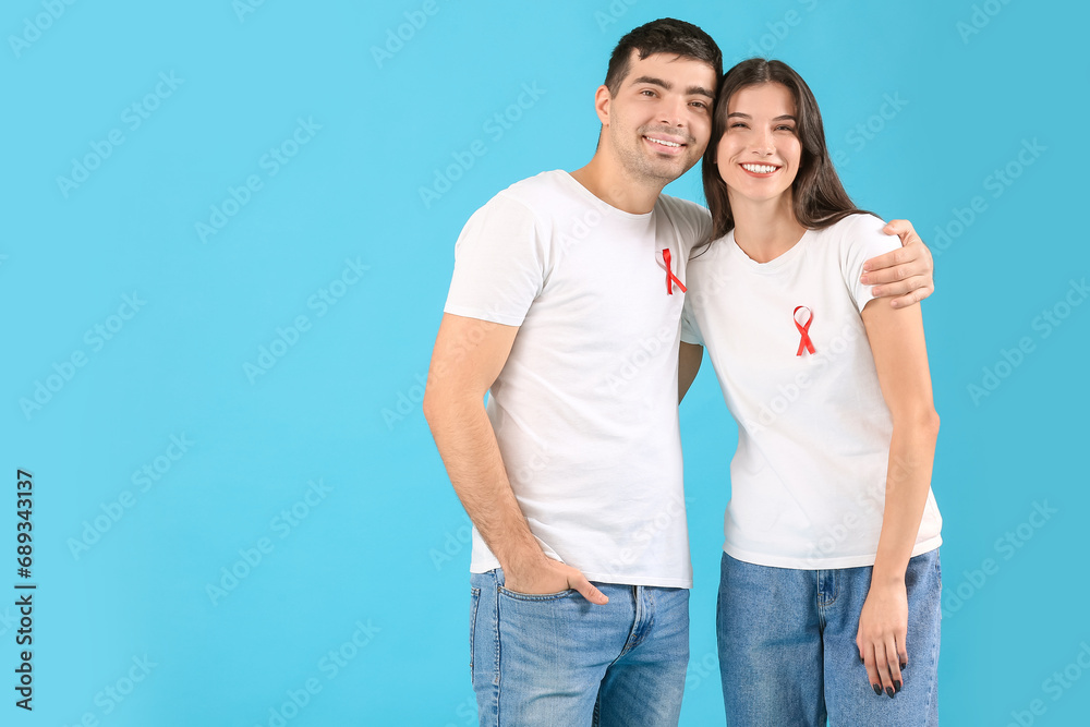 Young man and woman with red ribbons on blue background. World AIDS day concept Young man and woman with red ribbons on blue background. World AIDS day concept