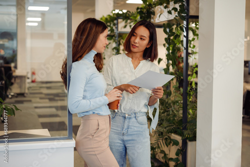 Diverse business women looking into some paperwork while standing in the office