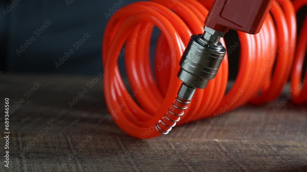 Worker connects orange air hose to air blow gun via hose coupling, closeup. Spiral hose for supplying air pressure to the instrument and possibility of working at a large distance from the main base