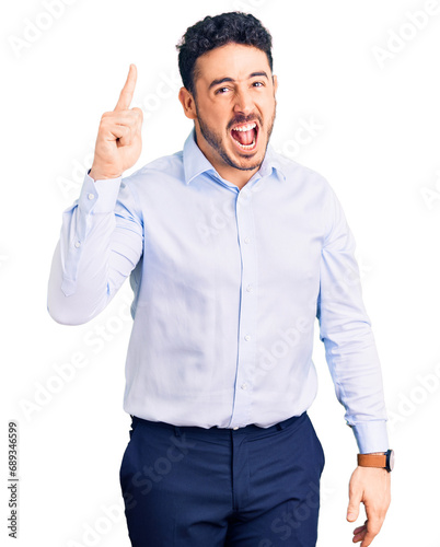 Young hispanic man wearing business clothes pointing finger up with successful idea. exited and happy. number one.