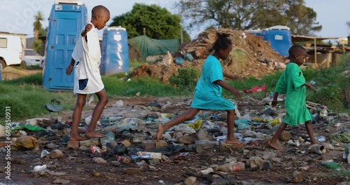 Poverty, Three poor Black African children playing around portable toilets and stinking effluent water in an informal settlement photo