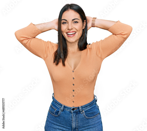 Young hispanic woman wearing casual clothes relaxing and stretching, arms and hands behind head and neck smiling happy