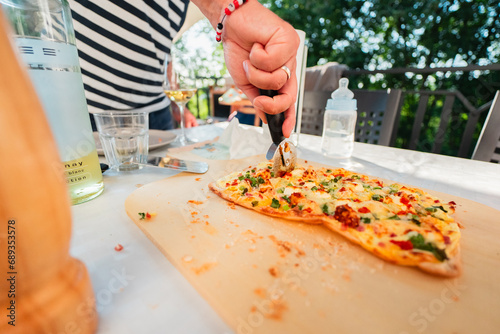 Cutting Through a French Tarte Flambe Flammekueche with Créme Fraiche Cheese Spring Onions with a Pizza Roller