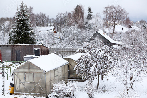 A personal plot with sheds, a greenhouse and fruit trees covered with snow photo