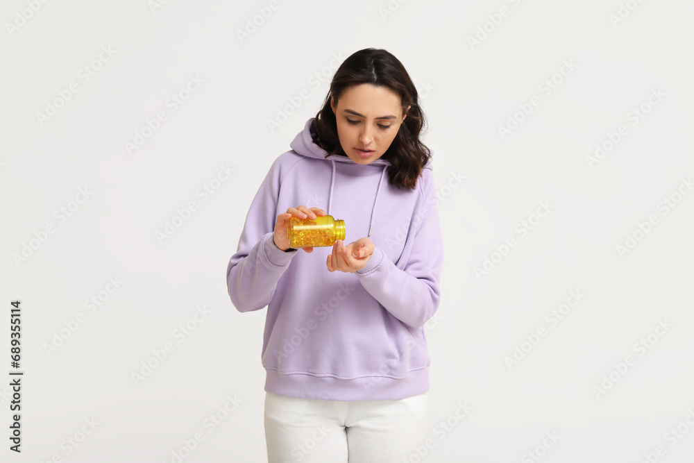 Sick young woman taking pill on light background Sick young woman taking pill on light background