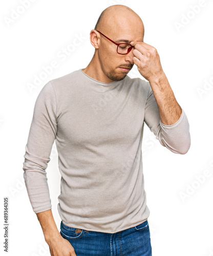 Bald man with beard wearing casual clothes and glasses tired rubbing nose and eyes feeling fatigue and headache. stress and frustration concept.