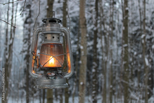 kerosene lantern shines near a fantasy scary tree in winter © Yar
