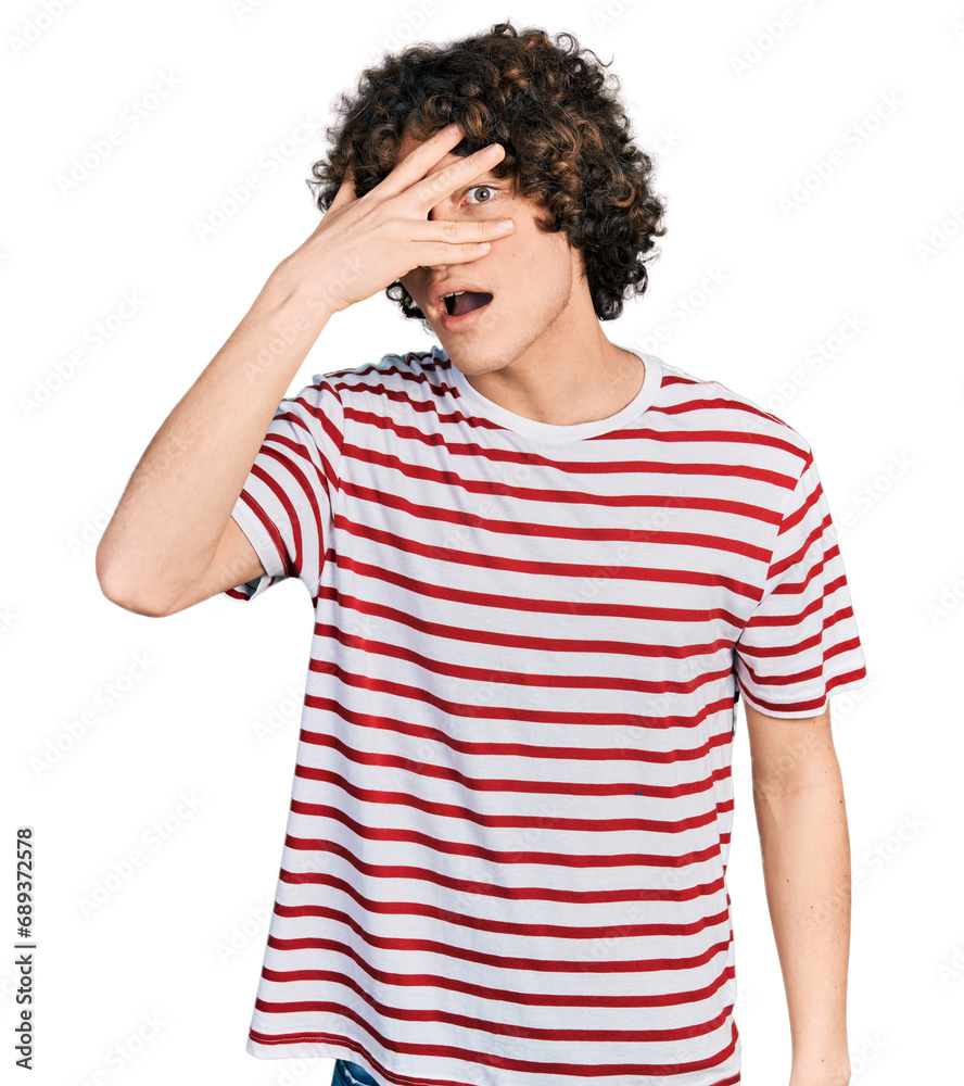 Caucasian teenager wearing casual clothes peeking in shock covering face and eyes with hand, looking through fingers with embarrassed expression. Caucasian teenager wearing casual clothes peeking in shock covering face and eyes with hand, looking through fingers with embarrassed expression.
