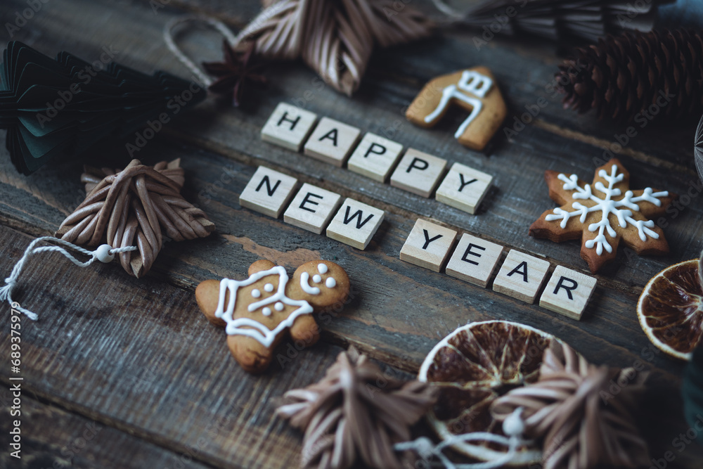 Happy New Year greeting written with wooden blocks . Holidays card on wooden background with gingerbread cookies, handmade craft toys, festive rustic zero waste decorations. Sustainable lifestyle Happy New Year greeting written with wooden blocks . Holidays card on wooden background with gingerbread cookies, handmade craft toys, festive rustic zero waste decorations. Sustainable lifestyle