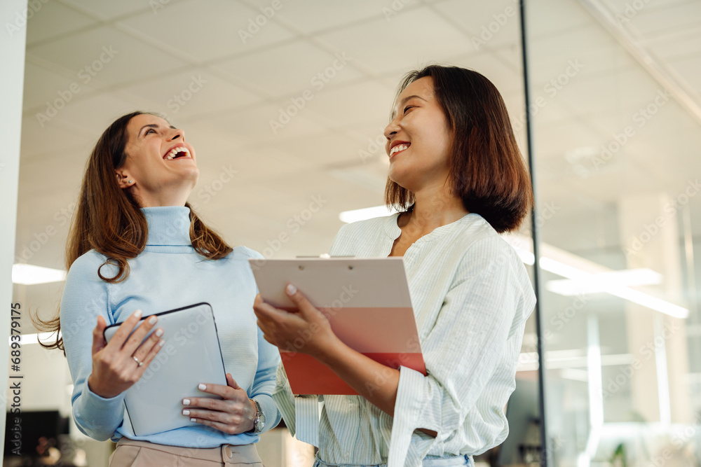Multiracial female colleagues smiling while having a meeting in the office Multiracial female colleagues smiling while having a meeting in the office
