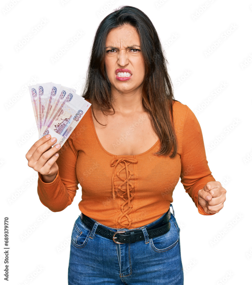 Beautiful hispanic woman holding russian 500 ruble banknotes annoyed and frustrated shouting with anger, yelling crazy with anger and hand raised Beautiful hispanic woman holding russian 500 ruble banknotes annoyed and frustrated shouting with anger, yelling crazy with anger and hand raised