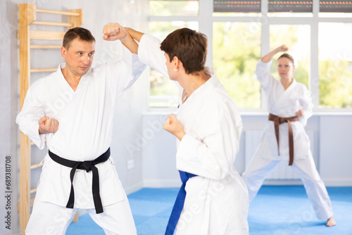 Young guy and man during martial arts karate class train to perform basic blows to opponent with their hands and feet. Preparation of athletes for competitions