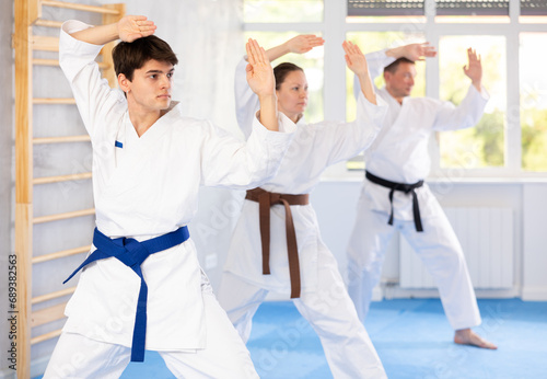 In gym, certified master coach conducts karate kata lesson with students and shows sequence of actions when conducting close fight