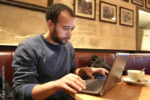 Man working on his laptop at a local coffee bar 