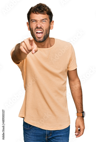 Handsome young man with beard wearing casual tshirt pointing displeased and frustrated to the camera, angry and furious with you