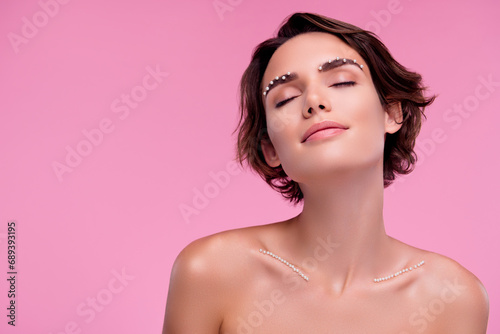 Portrait of elegant woman enjoying expensive 8 march present pearls decor on eye brows breast over pink background