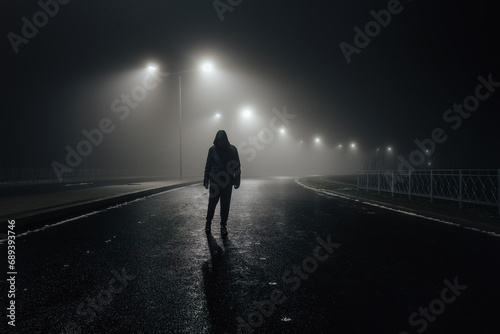 Sad man alone walking along the alley in night foggy road photo