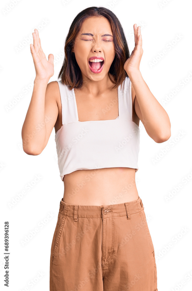 Young beautiful chinese girl wearing casual clothes celebrating mad and crazy for success with arms raised and closed eyes screaming excited. winner concept Young beautiful chinese girl wearing casual clothes celebrating mad and crazy for success with arms raised and closed eyes screaming excited. winner concept