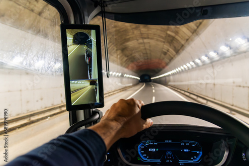 Fotografi View from the driving position of a truck of the interior of a highway tunnel and a screen as a rearview mirror, truck with rear vision cameras