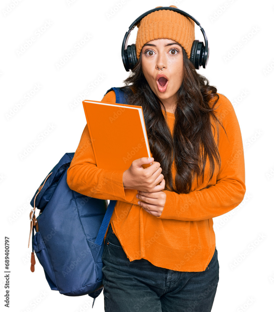 Beautiful brunette young woman wearing student backpack and holding books scared and amazed with open mouth for surprise, disbelief face Beautiful brunette young woman wearing student backpack and holding books scared and amazed with open mouth for surprise, disbelief face