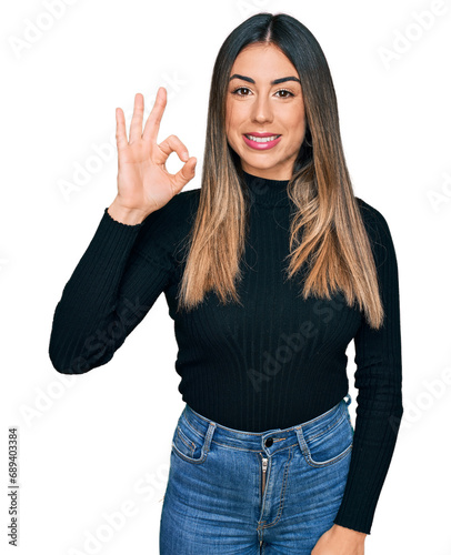 Fotografia Young hispanic woman wearing casual clothes smiling positive doing ok sign with hand and fingers