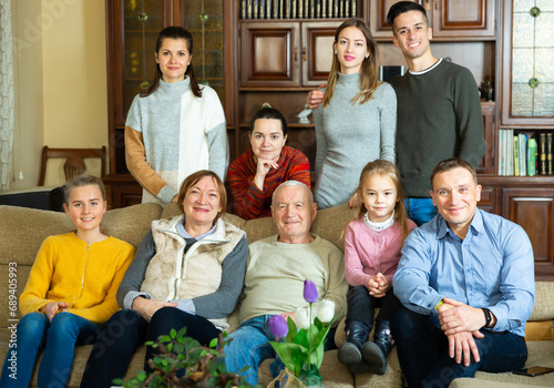 Portrait of big happy family gathering in parental home, posing together on couch